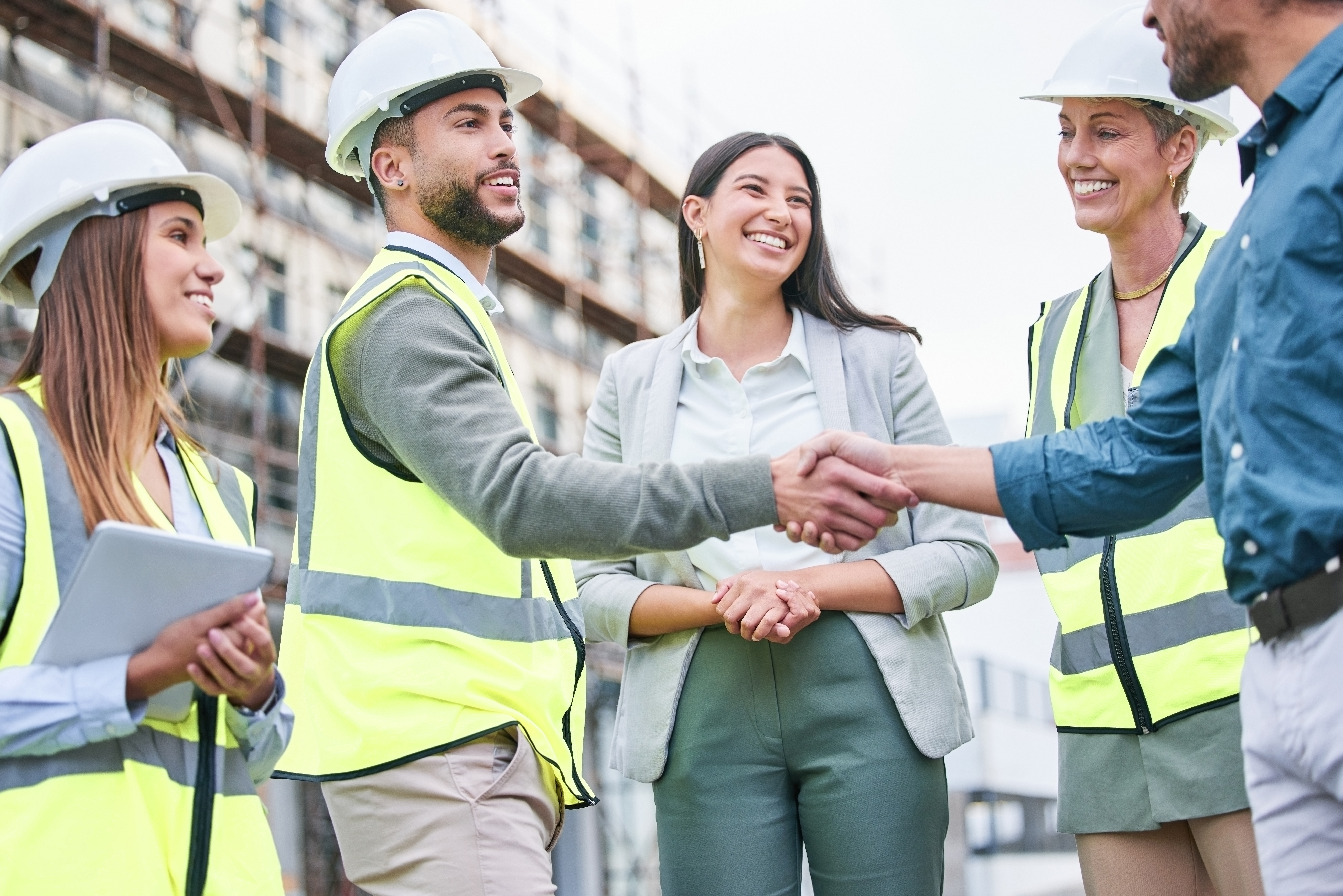 Shot of a team of builders shaking hands on a construction site outside.