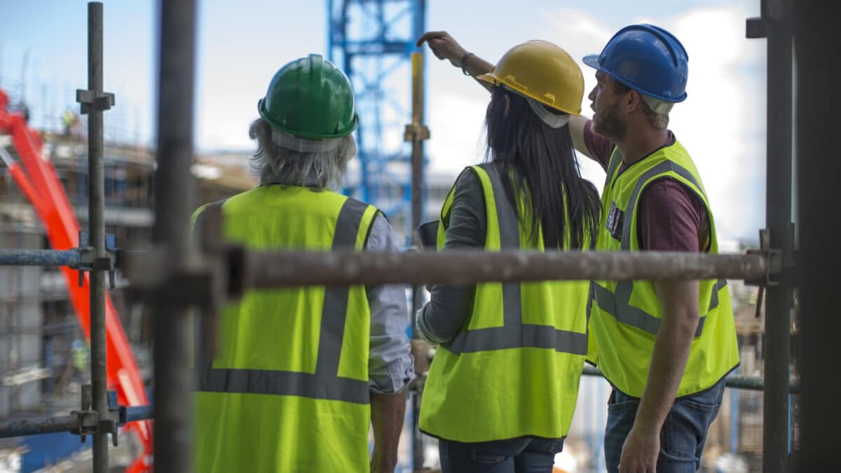 Construction worker talking to man and woman on a construction site